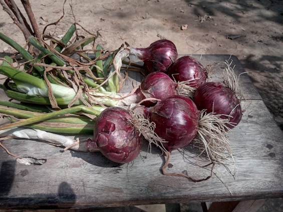 six onion bulbs on wooden table