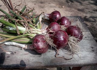 six onion bulbs on wooden table