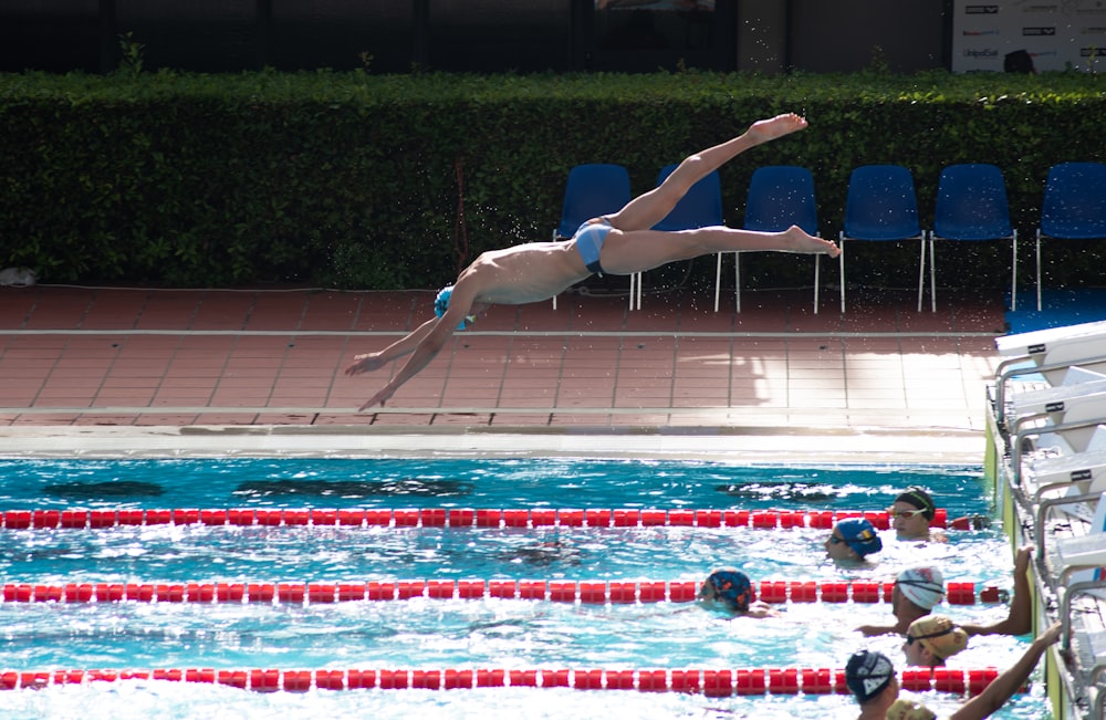man dive on swimming pool during daytime