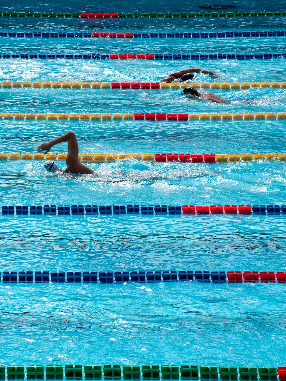 three person swimming on pool