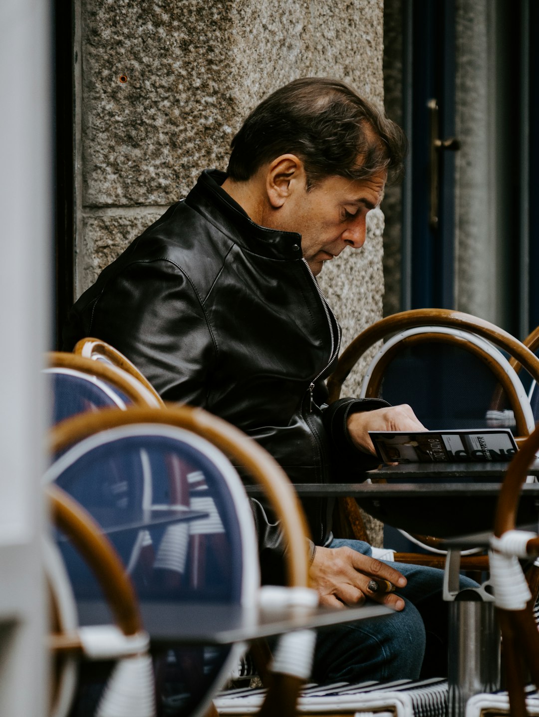 man in black leather jacket sitting outdoors