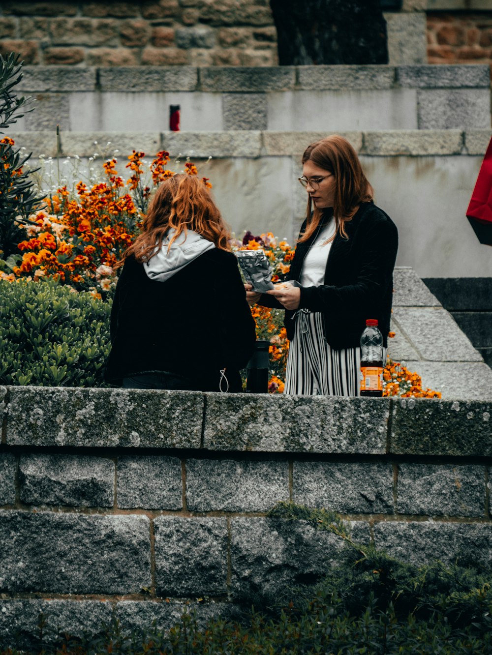 Femme lisant à côté d’une femme assise sur une surface en béton