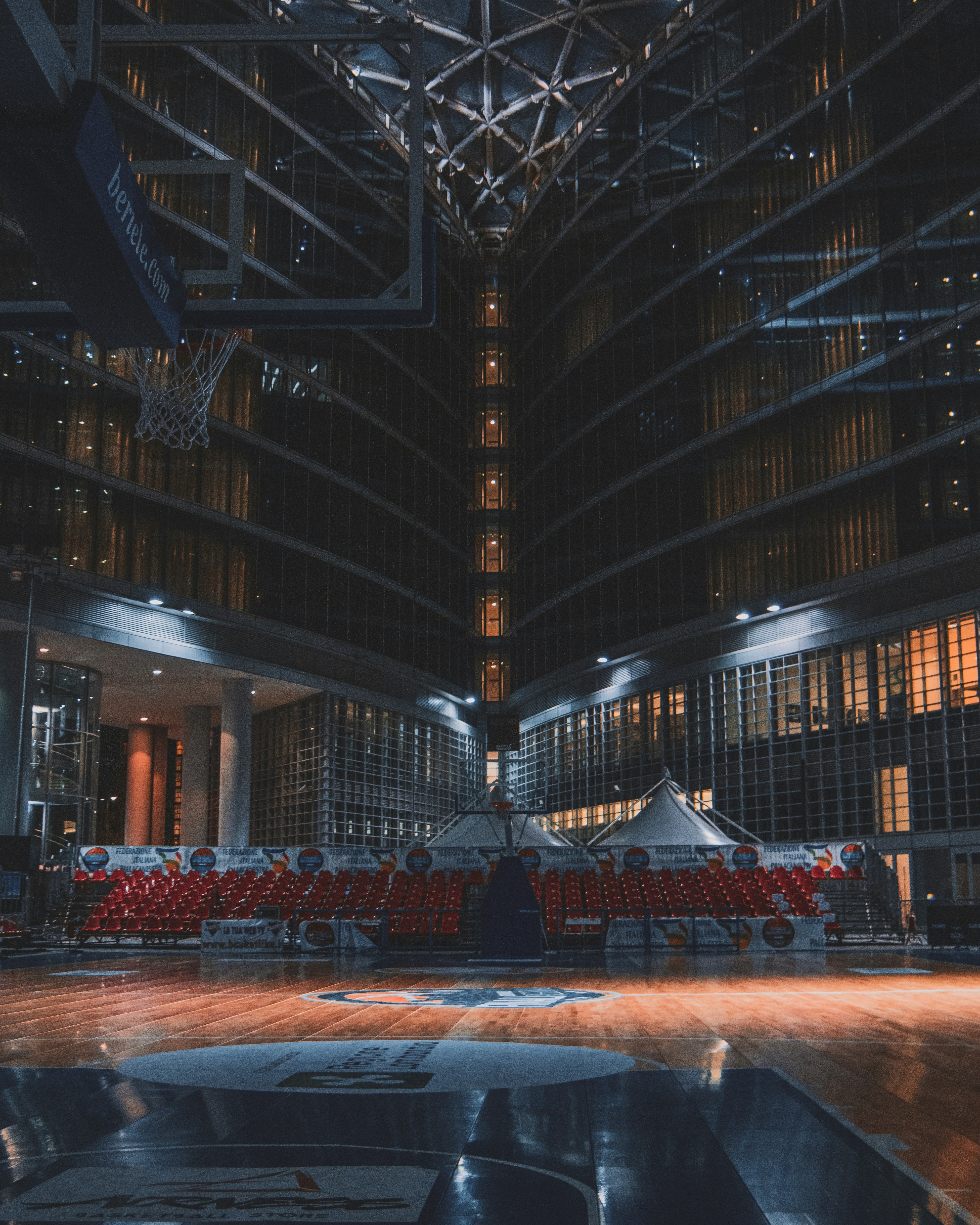 Basketball arena with dim overhead lights and empty dark seating in background