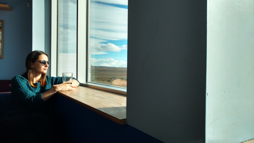 woman sitting beside window while looking outside