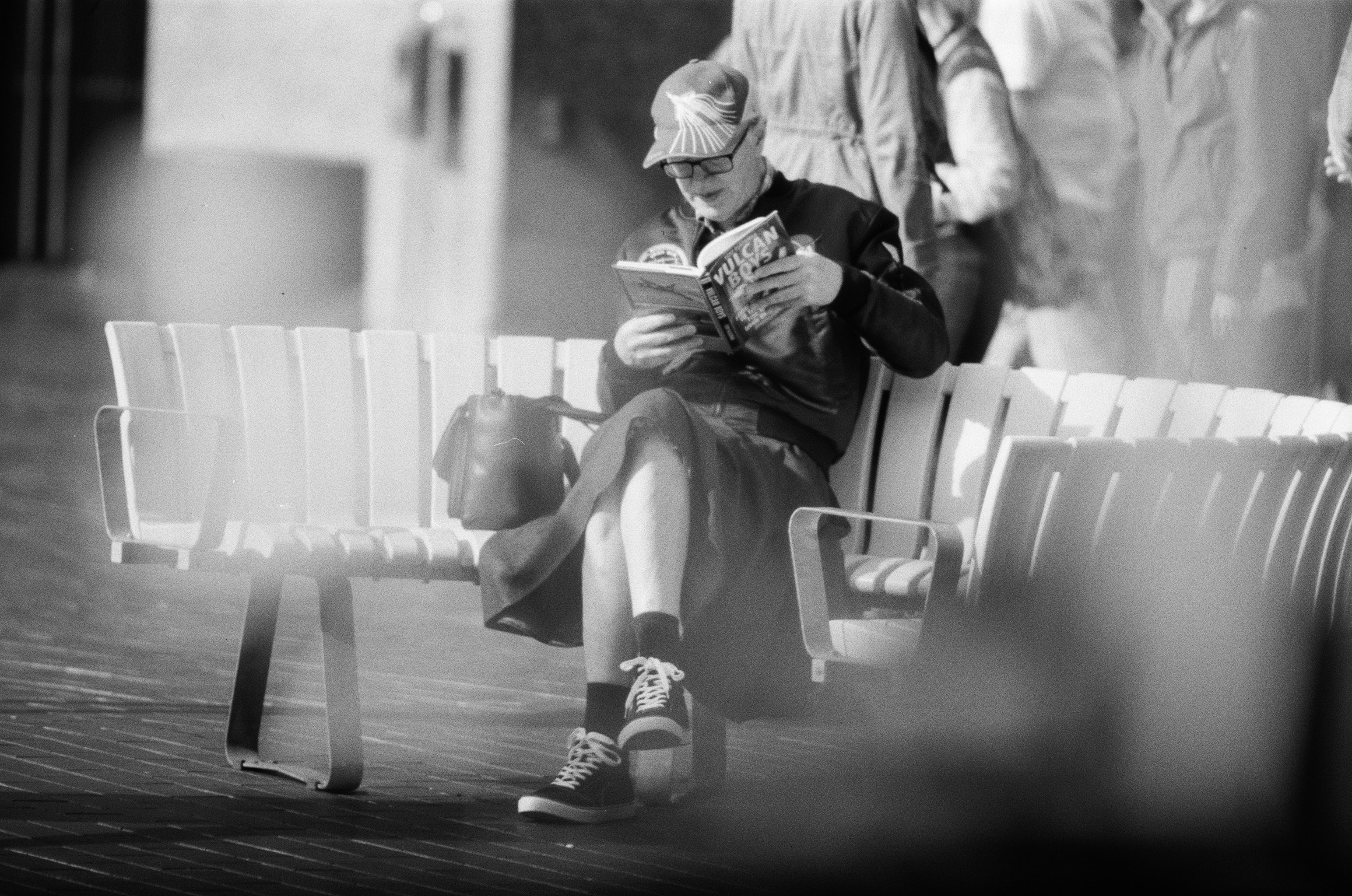 grayscale photography of man seated on bench