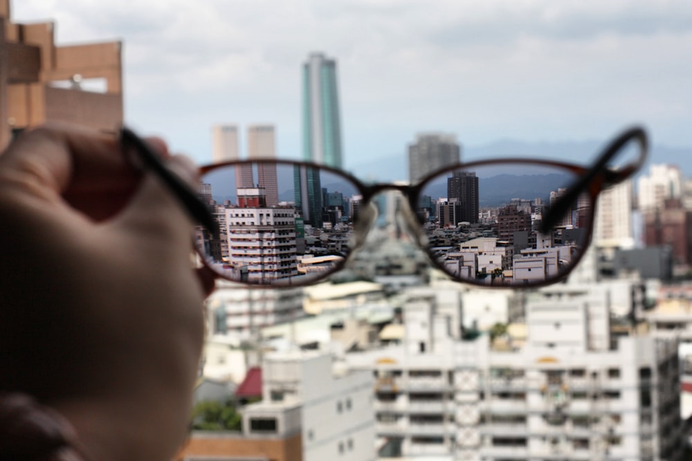 Gafas de montura negra con vista clara de los edificios de la ciudad