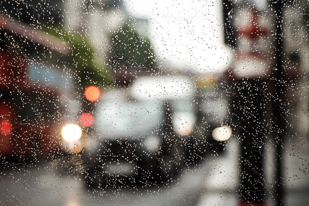voitures dans la rue vues à travers une vitre avec des gouttelettes d’eau