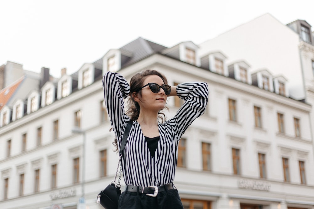 woman with both hands behind her head in front of building during day