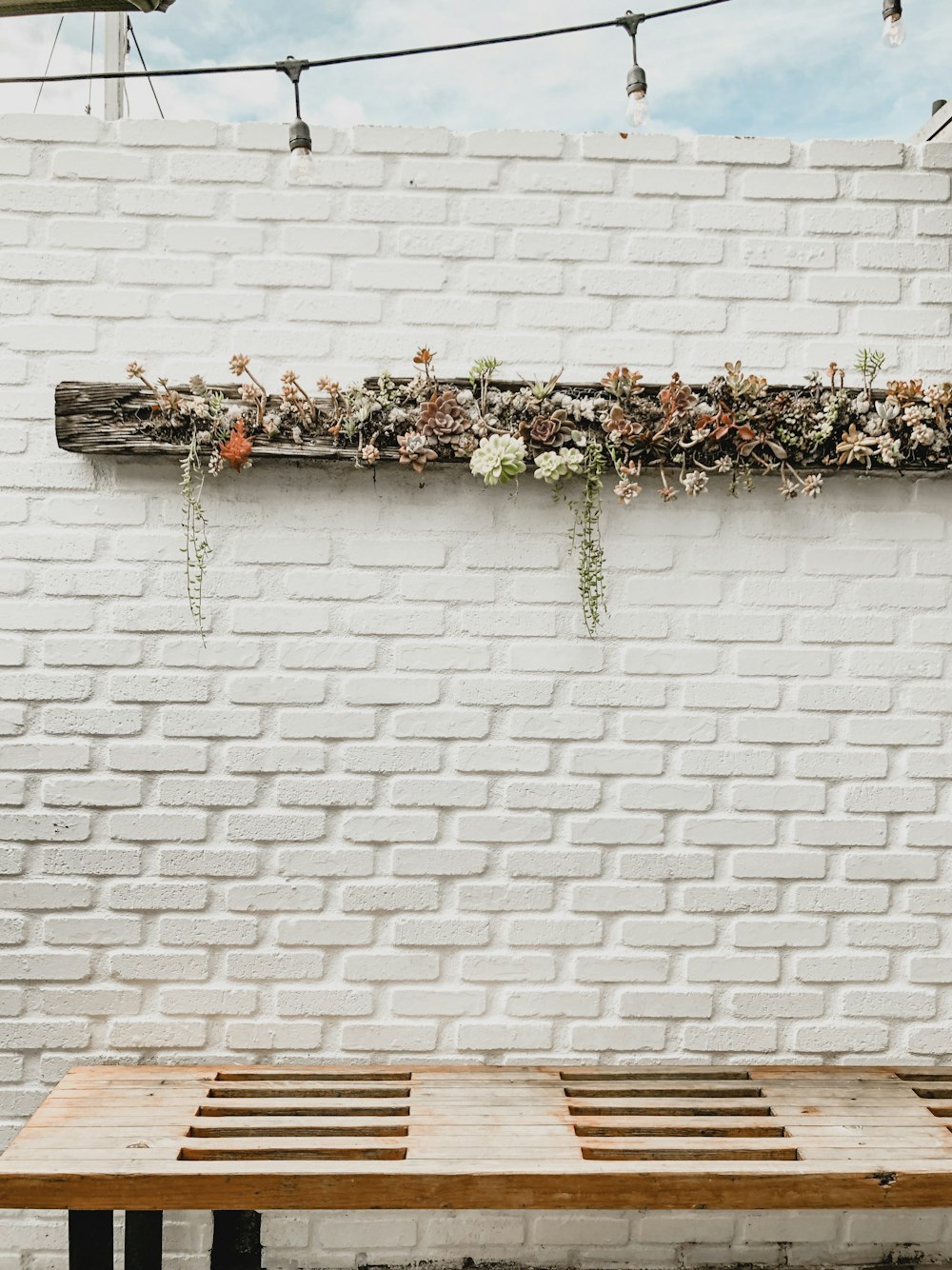 flowers on wooden beam mounted on brick wall above brown table