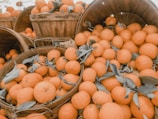 Bright oranges arranged in a rustic wooden box with leaves.