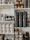 A display of several aluminium urns with matte finishes arranged neatly on shelves in a bright room.