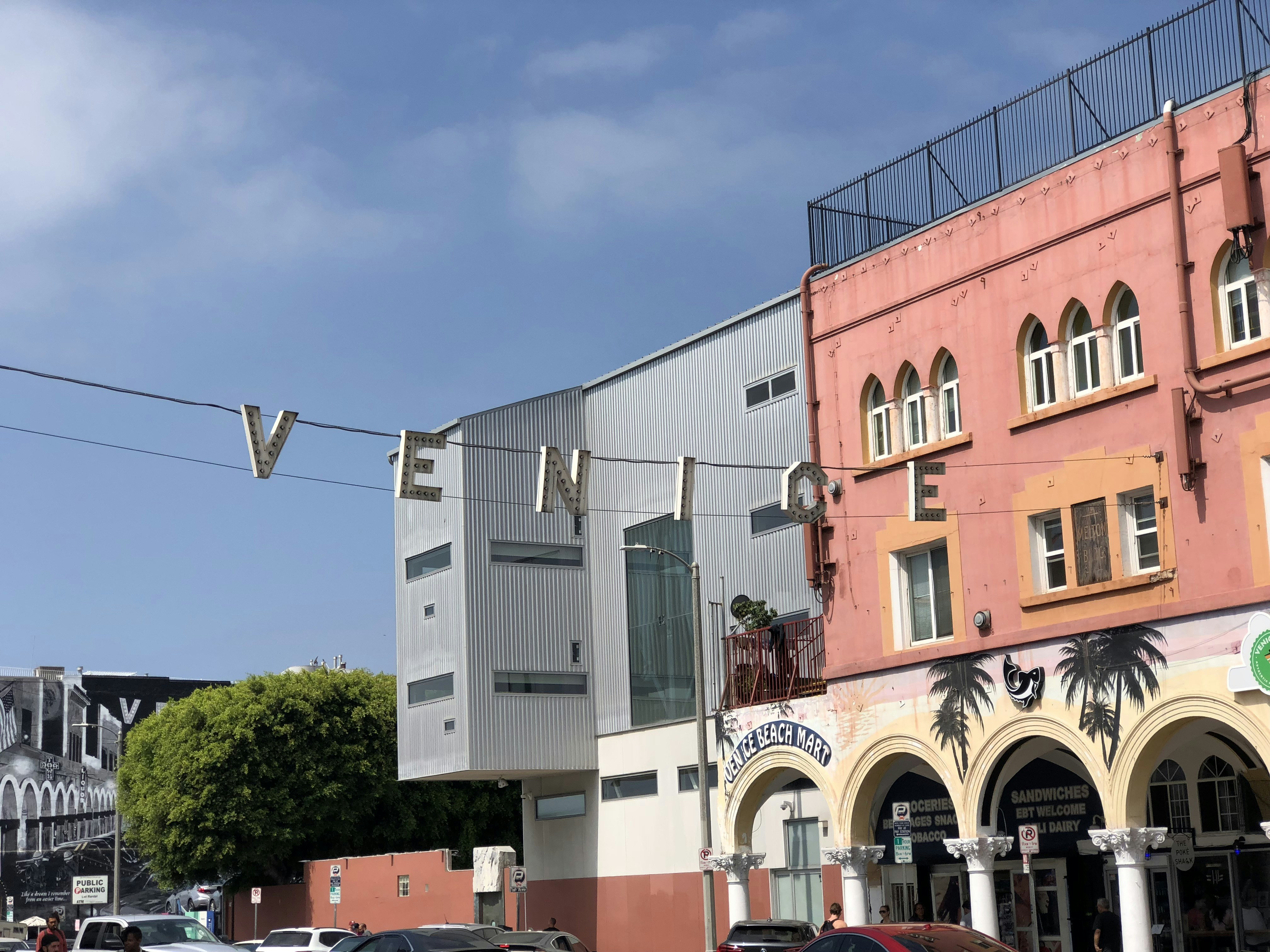Venice hanging sign above vehicles during daytime