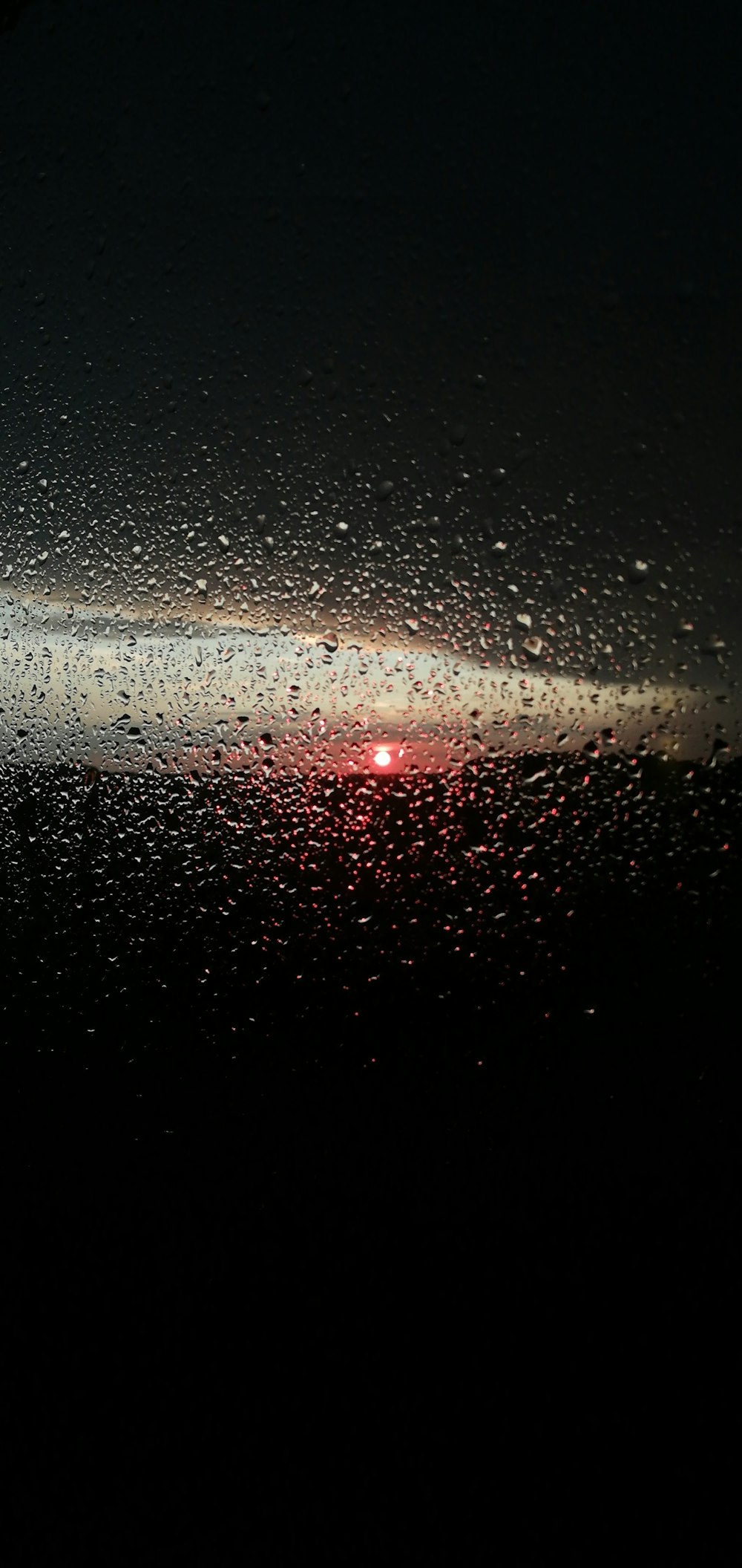 a view of the sun through a rain covered window