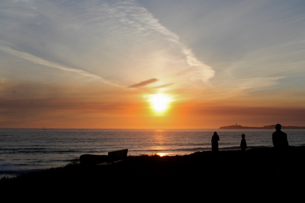 people standing on shore during golden hour