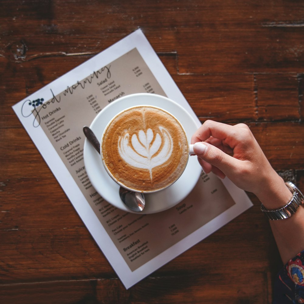 person holding white ceramic cup