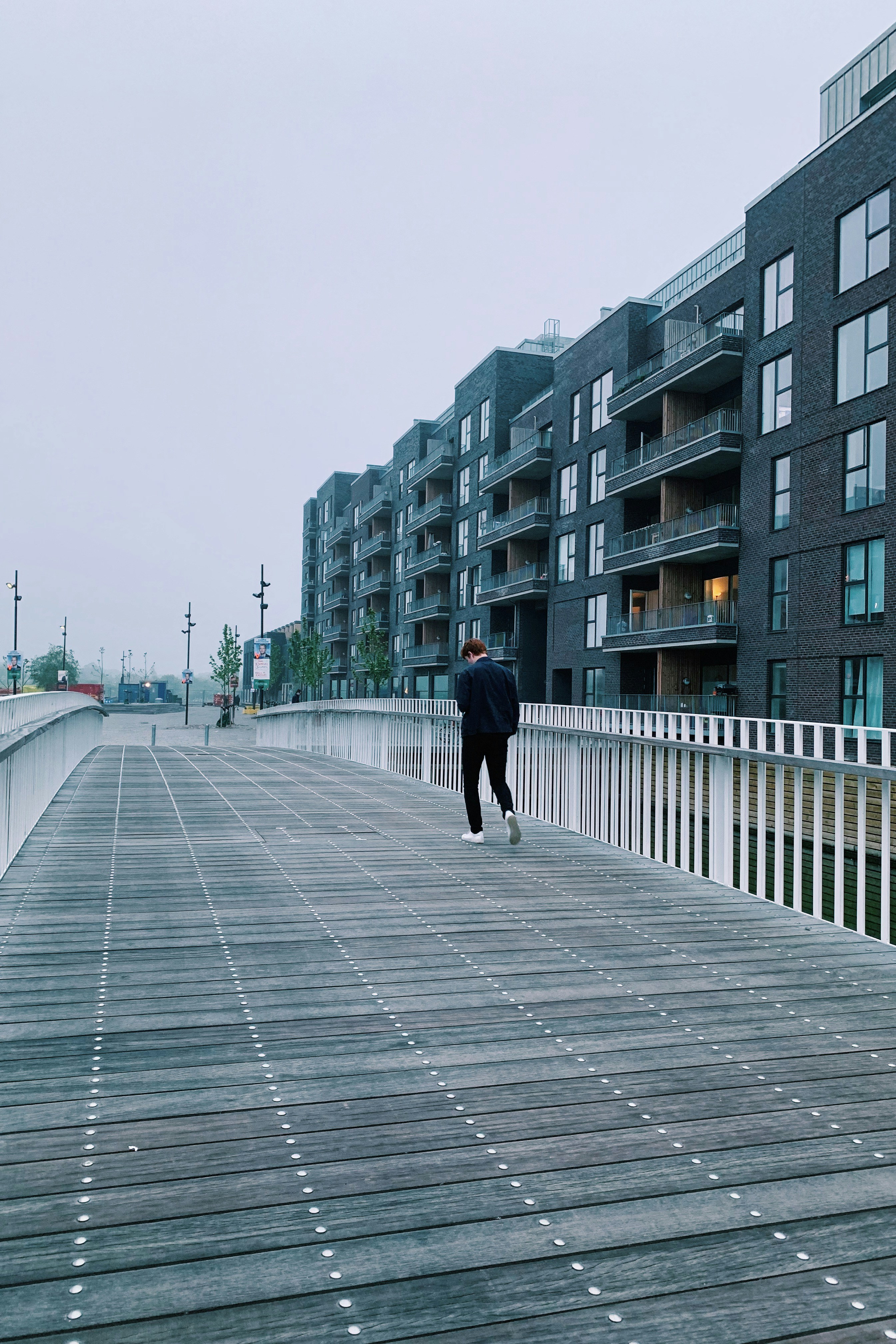 Man walking alone on pathway looking down beside high-rise buildings ...