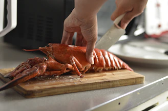 Chef inspecting a fresh lobster with a warm smile in a modern kitchen setting.