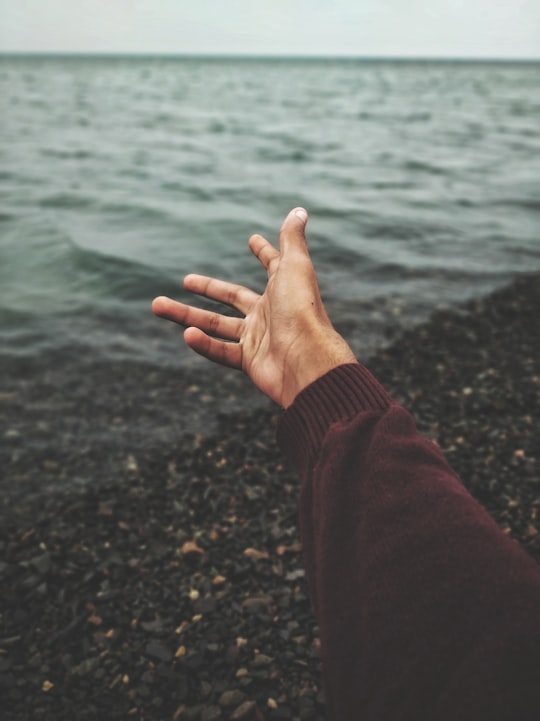 person raising hand near body of water in الغردقة Egypt