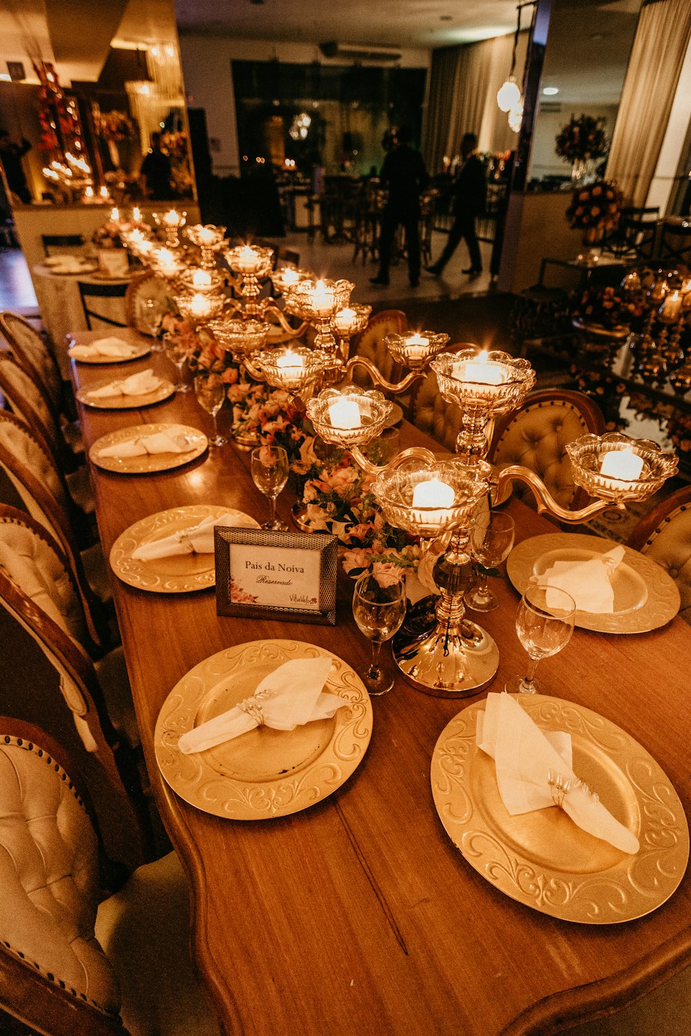 lighted tealight candles on table with complete table settings inside white room