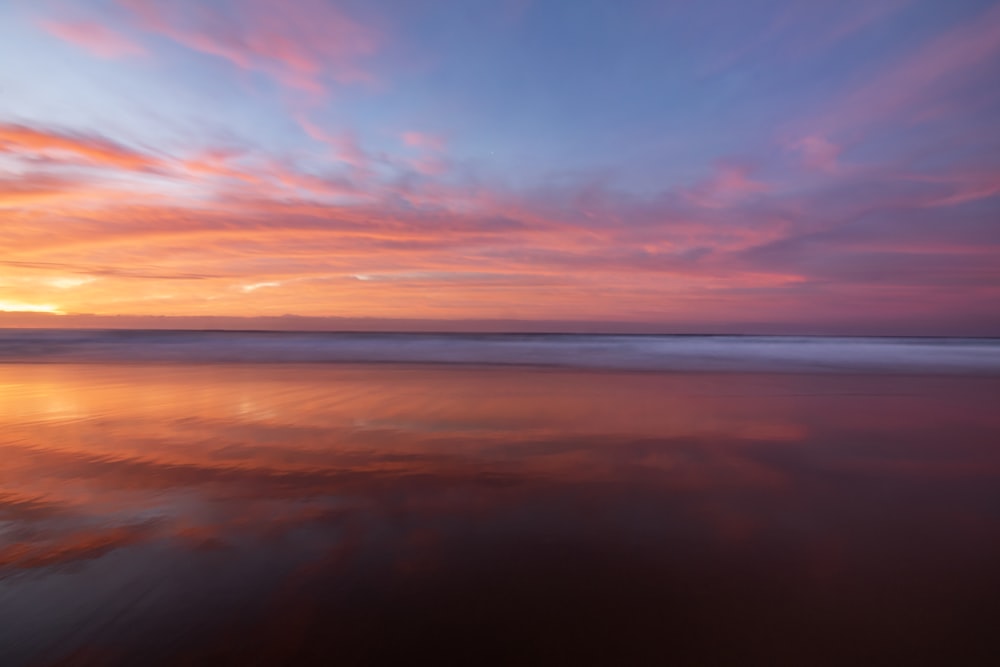 body of water under orange and blue skies