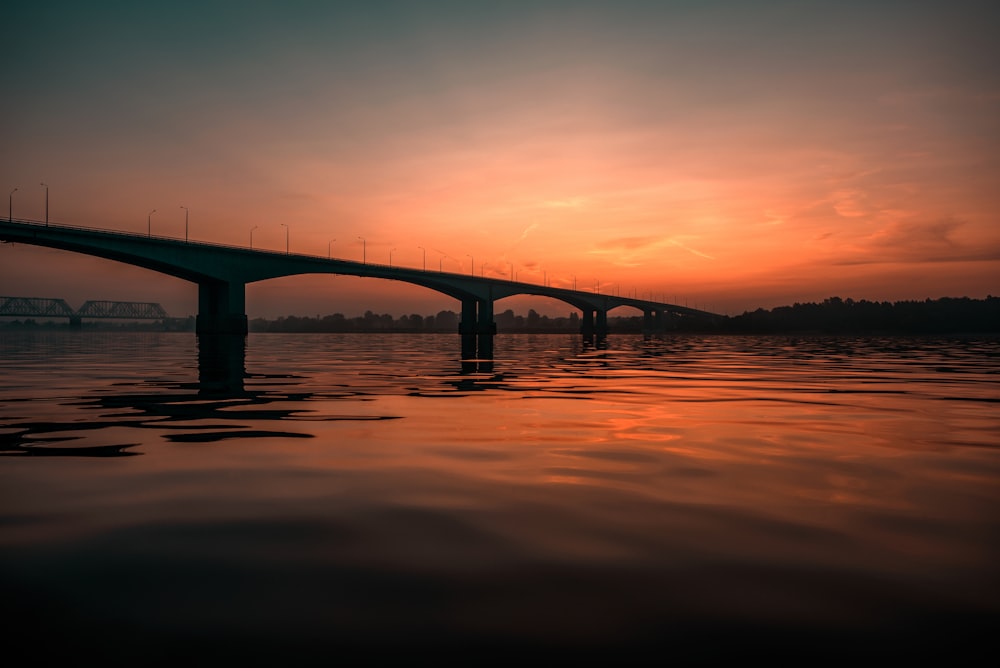 concrete bridge viewing sea under orange skies