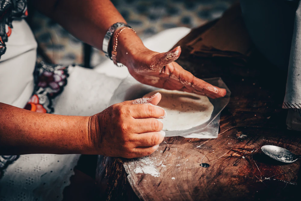 Hands pressing fresh masa into a tortilla