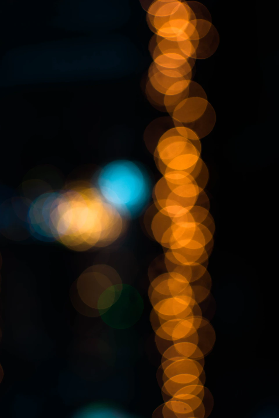 Black background features diagonal arrangement of slightly blurred orange circles in abstract pattern