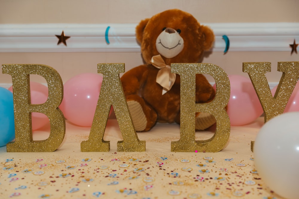 Baby freistehende Buchstaben in der Nähe von braunem Teddybär