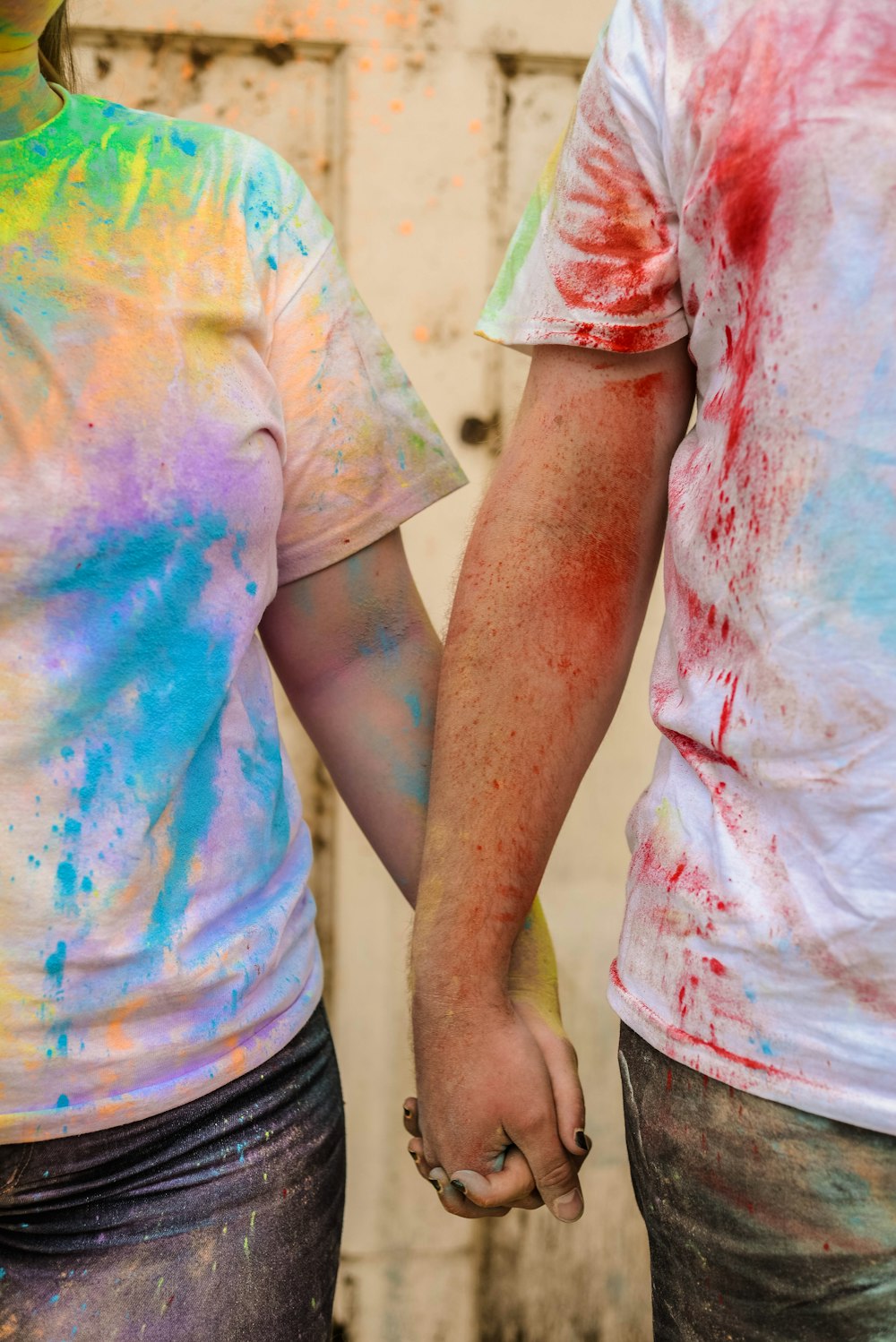 a man and a woman holding hands while covered in colored paint