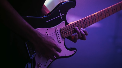 man playing black and white electric guitar