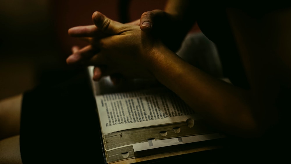 person praying with open bible on lap