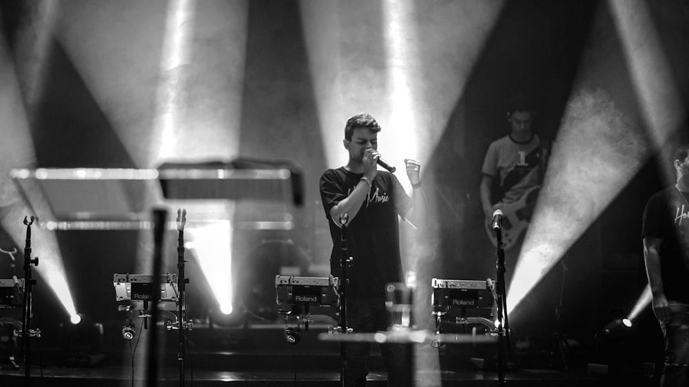 grayscale photo of man performing on stage