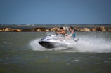 Two riders laughing as they speed across the waves on their jetskis.