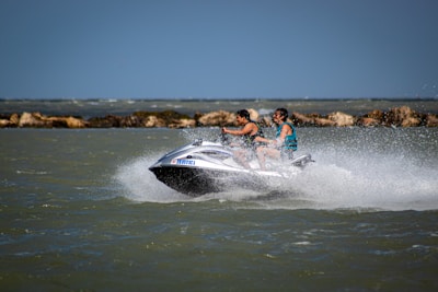 Two riders laughing as they speed across the waves on their jetskis.
