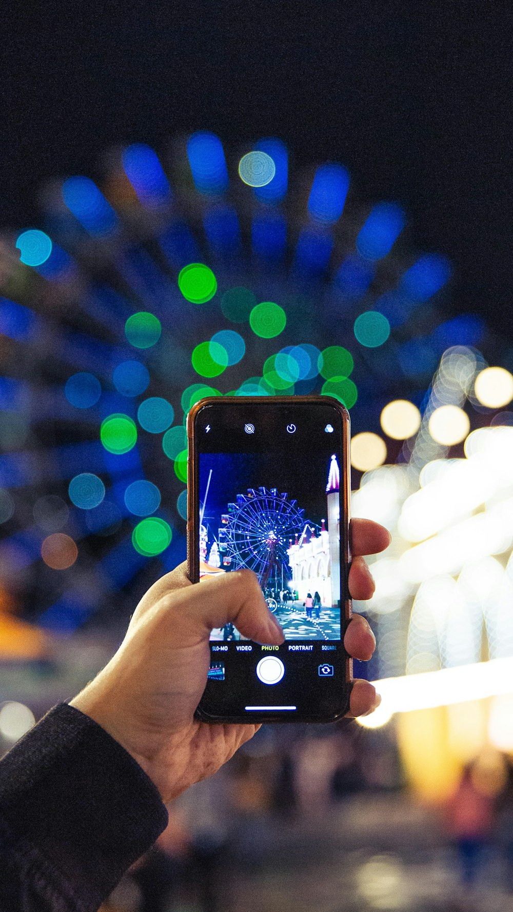 person holding smartphone displaying camera flashing the Ferris wheel