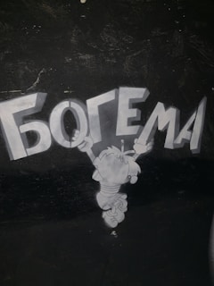 A cartoon character is jumping or hovering in the air with arms extended upward, reaching toward the large, bold Cyrillic text above it. The background is dark, and the character is depicted in shades of gray.