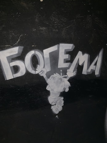 A cartoon character is jumping or hovering in the air with arms extended upward, reaching toward the large, bold Cyrillic text above it. The background is dark, and the character is depicted in shades of gray.