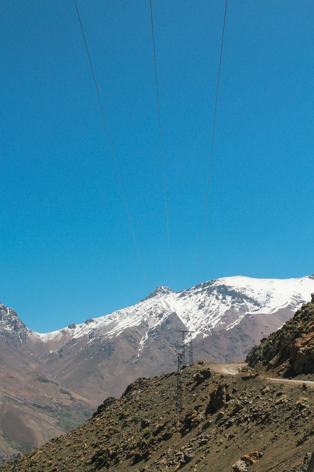 Linee di trasmissione di energia sul pendio della montagna sotto il cielo blu limpido