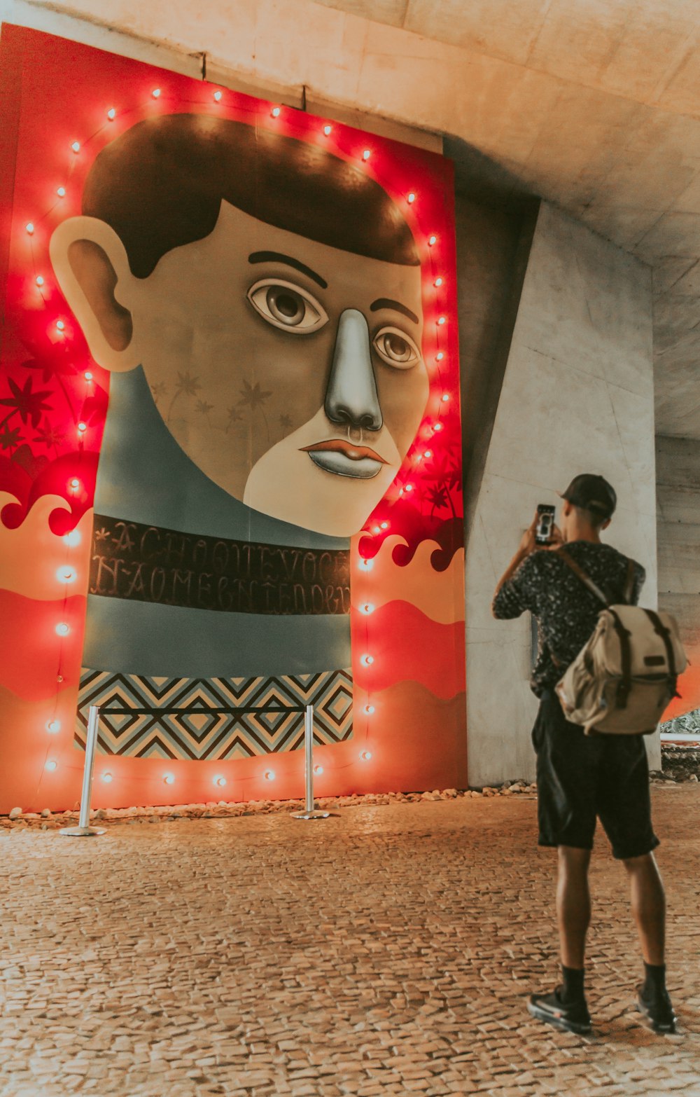 uomo che scatta foto del murale illuminato della parete del viso dell'uomo