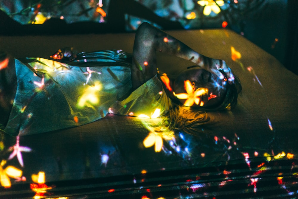 woman lying on bed with reflection of flowers