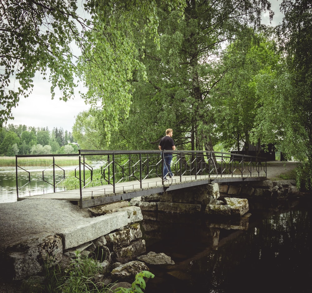 man walking on bridge near trees