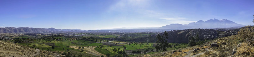 A panoramic view of Rancho El Rosario's lush green fields under a clear blue sky.