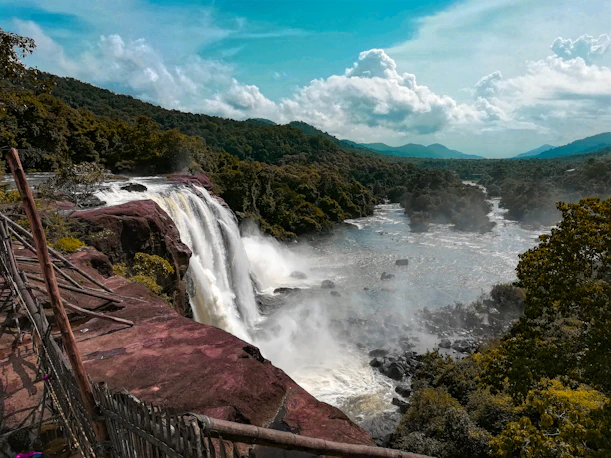 waterfalls under white and blue cloudy sky