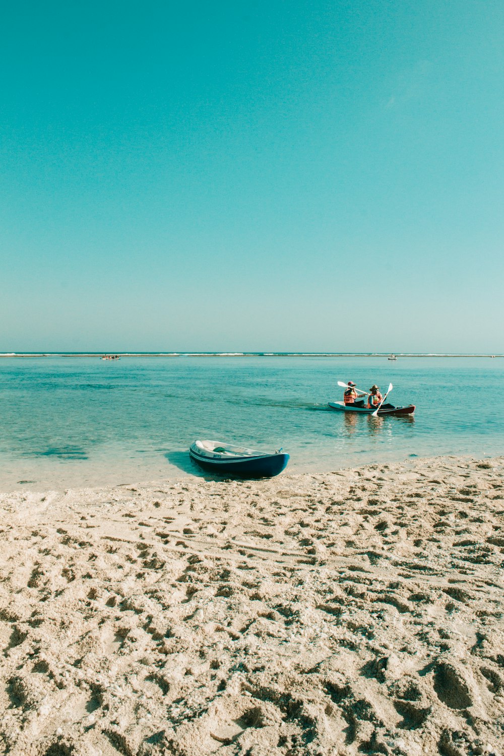 two person riding kayak on the beach
