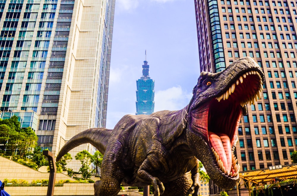 dinosaur with open mouth beside buildings still selective focus photography of