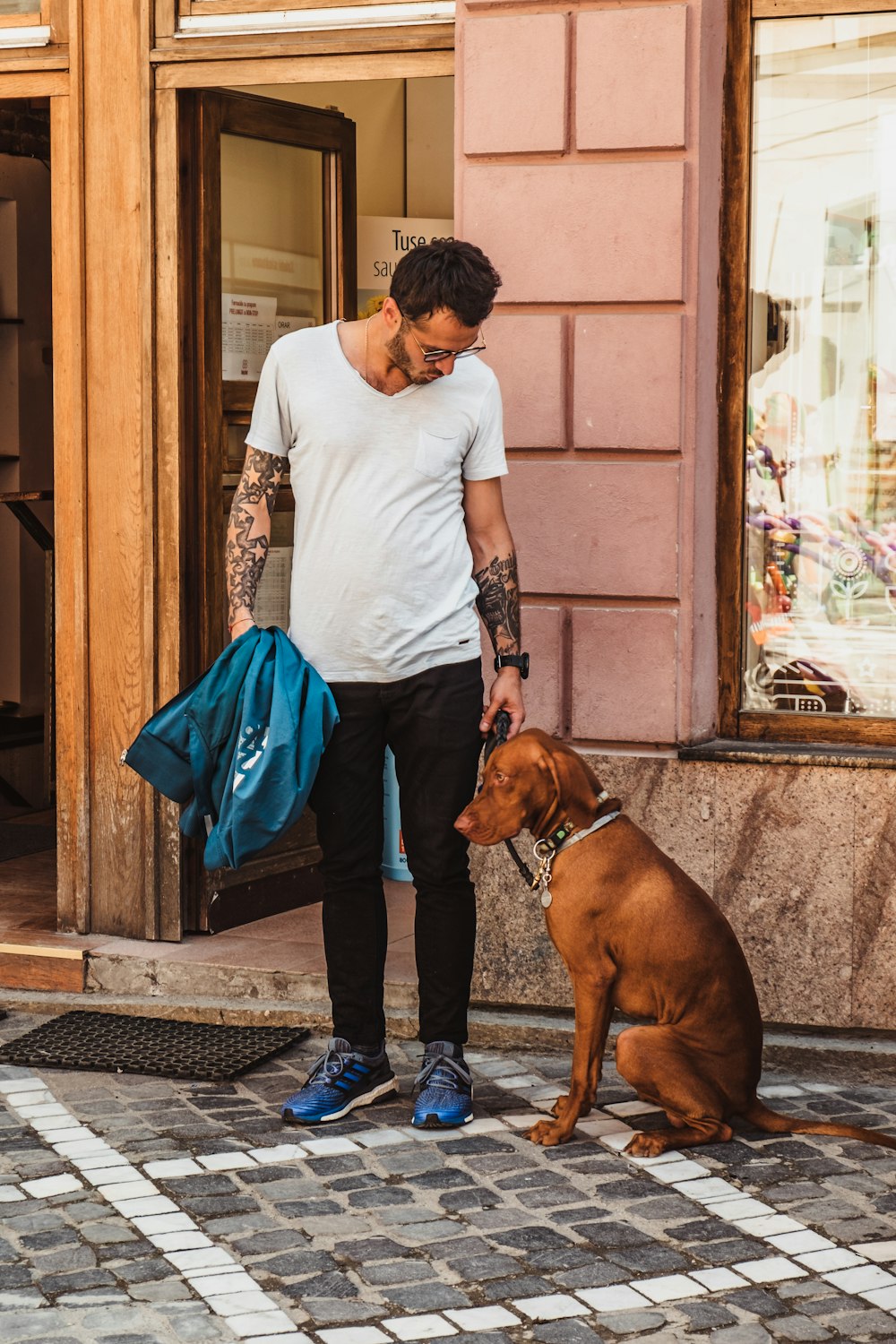 man standing beside sitting dog near open door of building