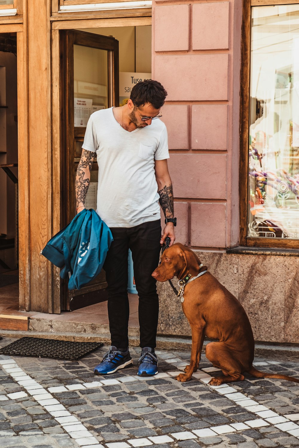 Mann steht neben sitzendem Hund in der Nähe der offenen Tür des Gebäudes