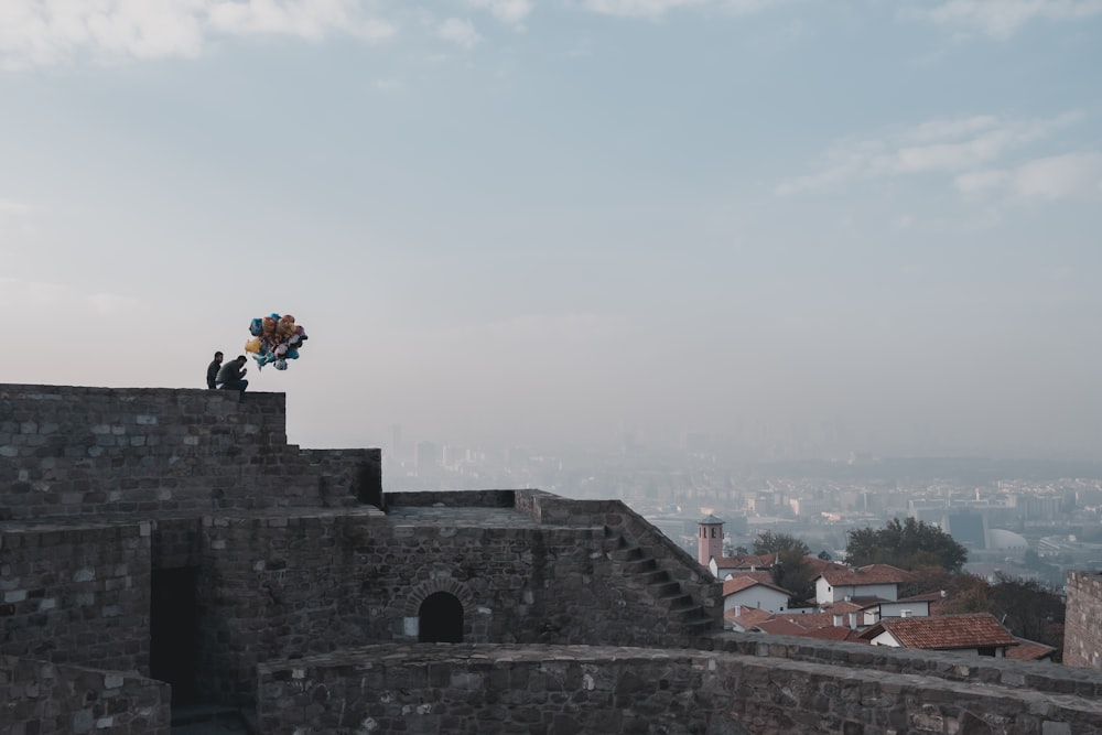 풍선 뭉치가 있는 건물 꼭대기에 서 있는 남자와 아이의 항공 사진
