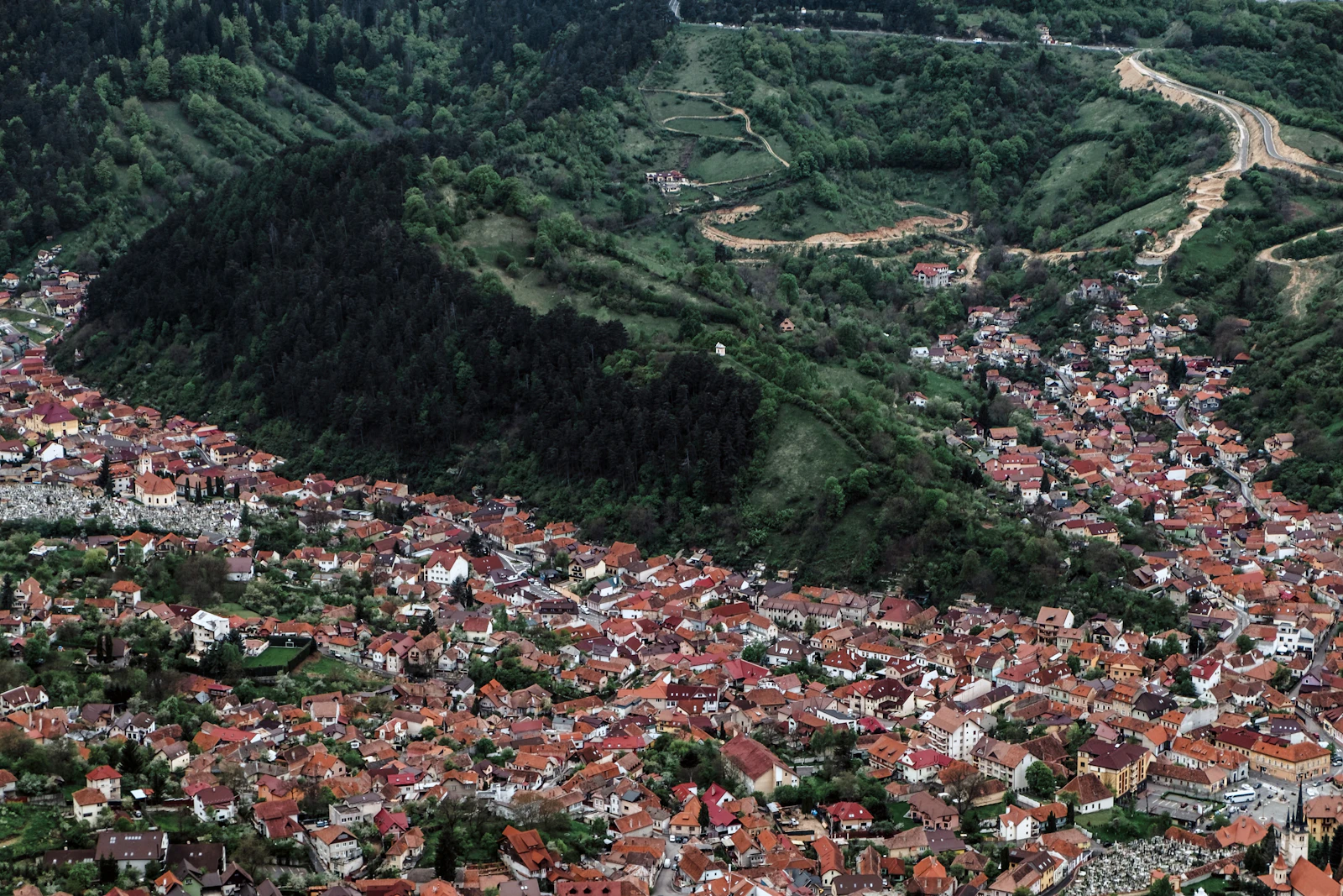Red roofs of Brașov below a wooded mountain