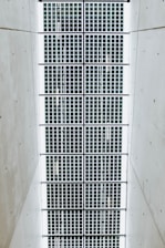 A symmetrical pattern of rectangular solar panels arranged in a grid. The panels are bordered by a light structure, and the surrounding area is a plain, smooth surface.
